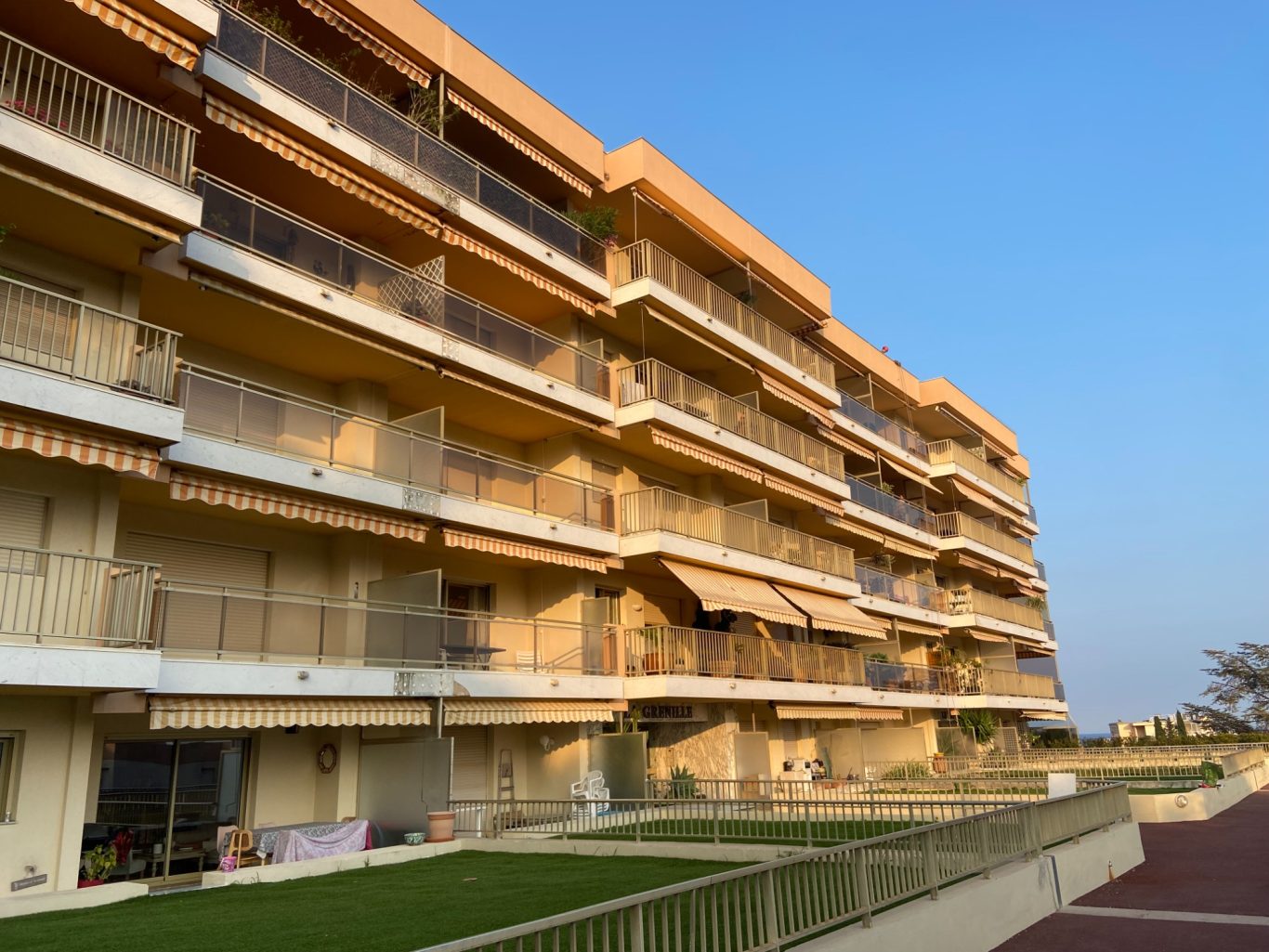 Bâtiment moderne à plusieurs étages avec balcons, sous un ciel bleu clair.